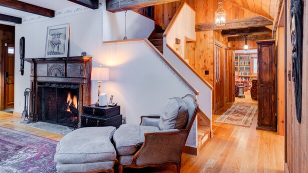 Una sala de estar acogedora con chimenea, una escalera y una estantería.