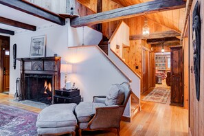 Een gezellige woonkamer met een open haard, een trap en een boekenplank.