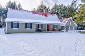 Charming two-story house with a cozy front porch and a warm red door.