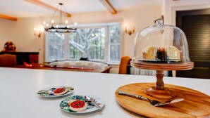 Una zona de comedor con una mesa de madera, un expositor de vidrio para pasteles y platos con comida.