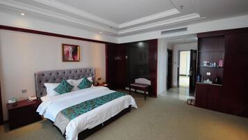 A hotel room with a large bed, a nightstand, a chair, a desk, and a wardrobe.