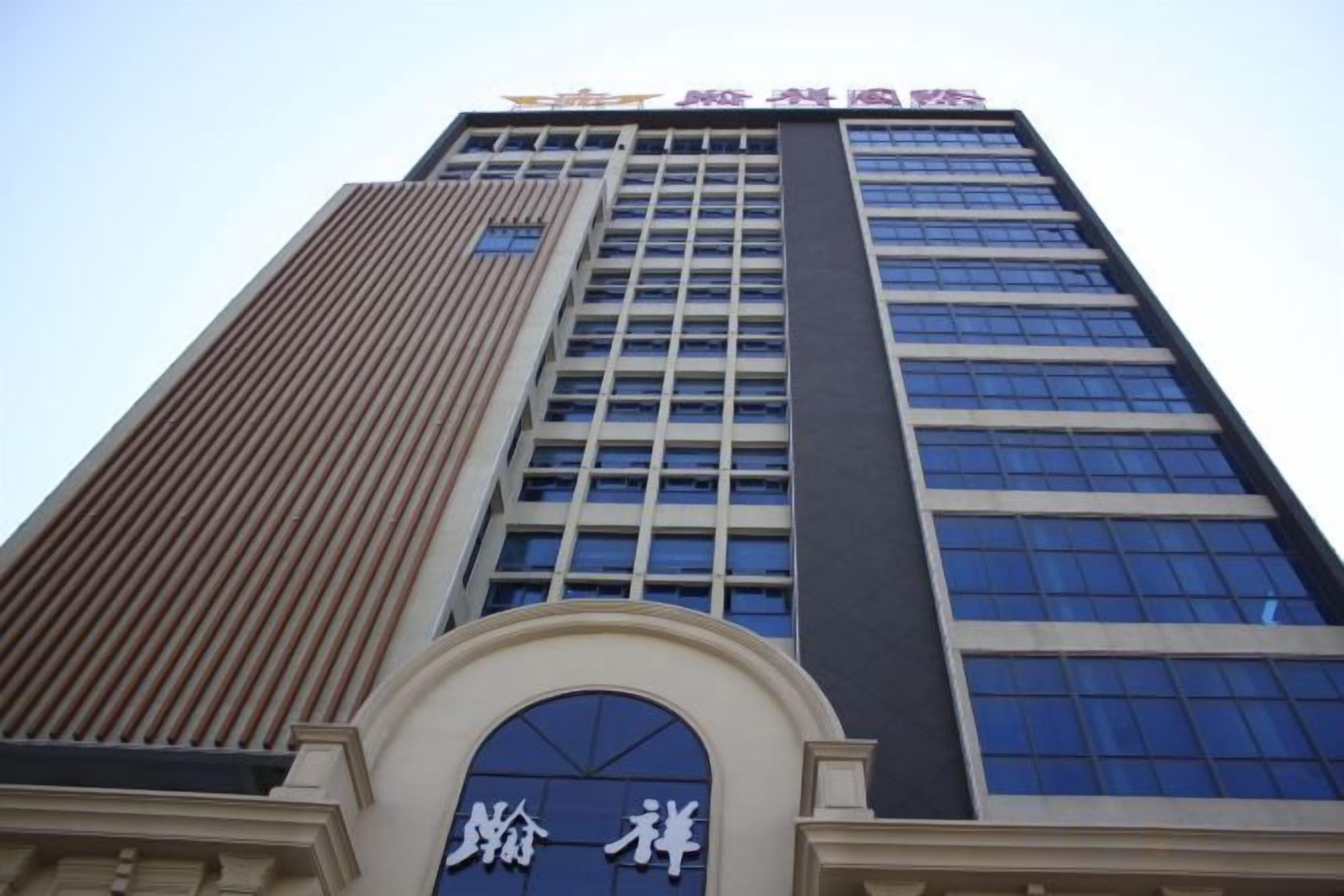 Un edificio alto con una entrada destacada que presenta un arco circular y un cartel con caracteres chinos.