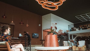 Un vestíbulo amplio con diseño moderno, que incluye un mostrador de recepción de madera, zonas de estar cómodas y una lámpara de techo original.
