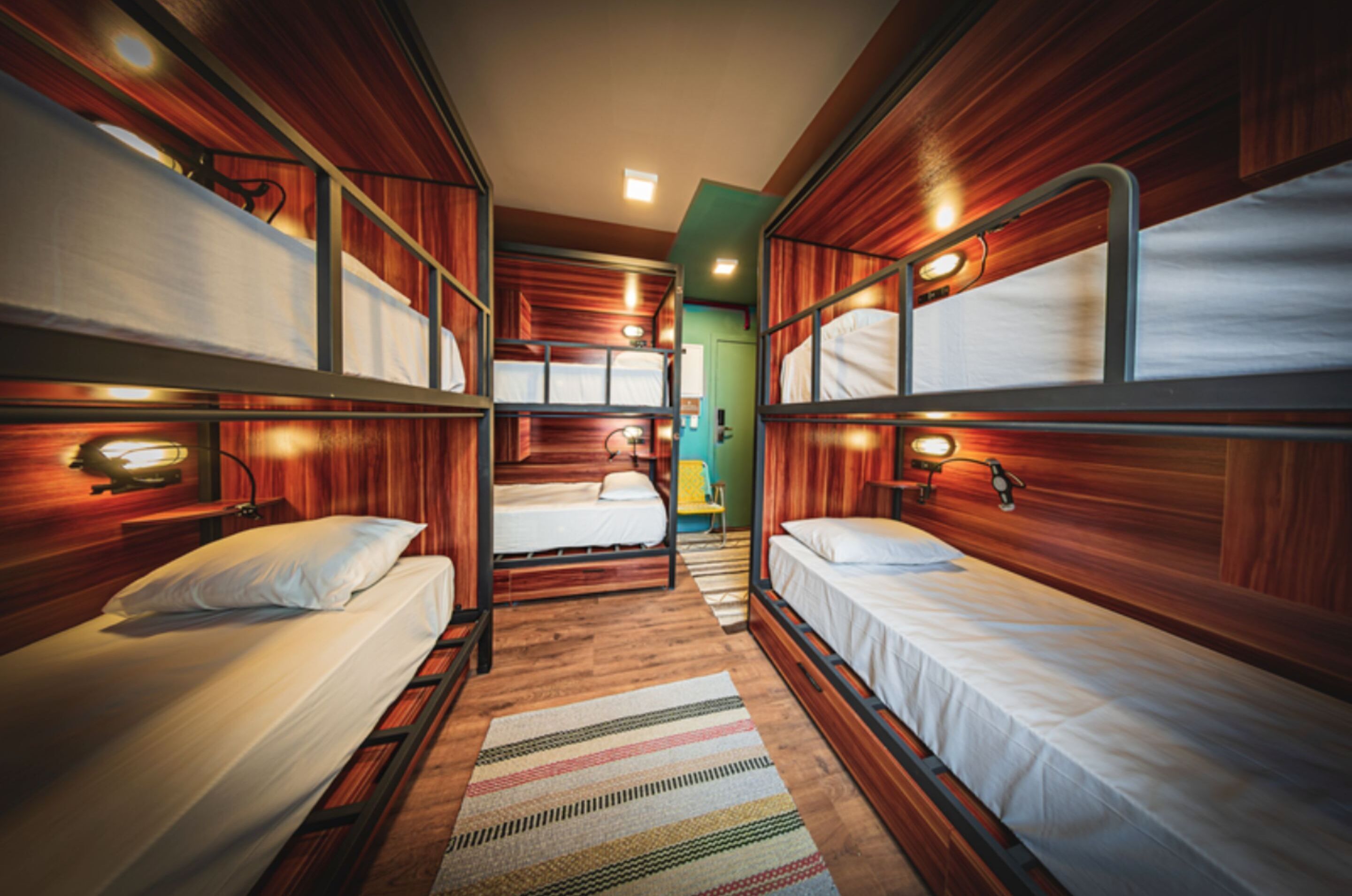 A compact, wood-paneled room with bunk beds and a striped rug.