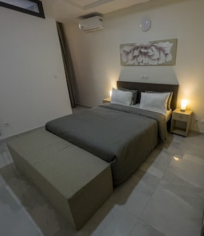 Une chambre moderne avec un grand lit, des tables de chevet, un appareil de climatisation et un élément décoratif mural.