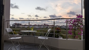 A balcony with two white chairs, a small round table, and a view of a residential area with houses and a cloudy sky. - Le Quartz - Luxury 2 Bed Room Apartments with sea view or overlooking the city (Abidjan)
