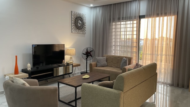 A modern living room with a flat-screen TV, sofa, armchairs, and a coffee table. - Le Quartz - Luxury 2 Bed Room Apartments with sea view or overlooking the city (Abidjan)
