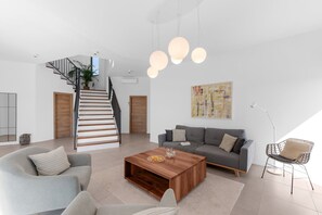 Uma sala de estar moderna com escada, sofá cinza, mesa de centro e um quadro na parede.