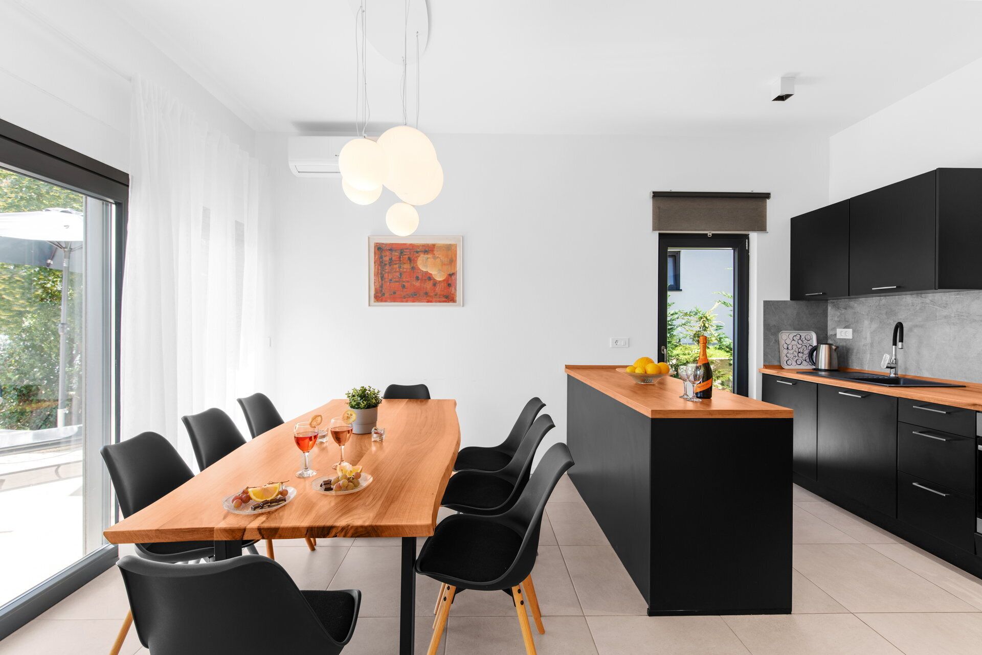 A modern kitchen with black cabinets, a wooden dining table, and a black island.