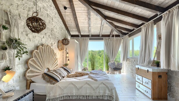 A rustic bedroom with a bed, a wooden chest of drawers, and a view of greenery outside. - Villa Belle with Pool (Vižinada)