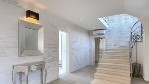 A modern interior with white brick walls, a large mirror, a fireplace, and a spiral staircase. - Villa Belle with Pool (Vižinada)