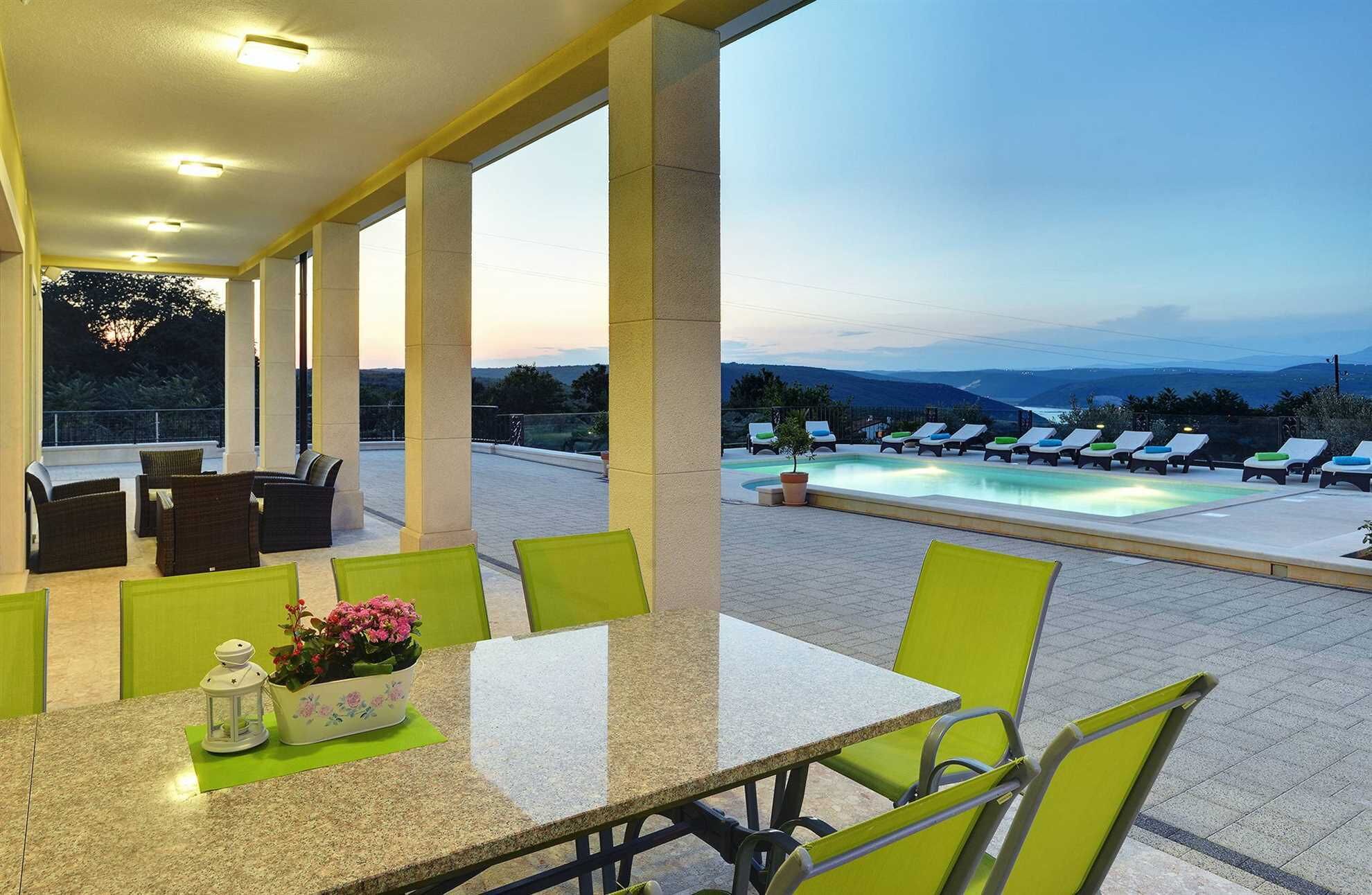 A terrace with a pool, outdoor seating, and a view of the mountains.