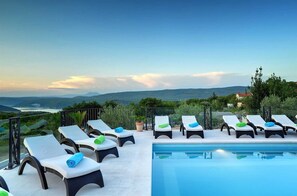 A poolside area with lounge chairs and a view of the landscape. - Villa Luce del Sole with Pool (Krnica)