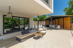 Ein moderner Außenbereich mit einer Couch, Sesseln und einem Esstisch.
