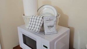 Un microondas con un cesto que contiene una bolsita de café, un rodillo de papel de cocina y platos de vidrio.