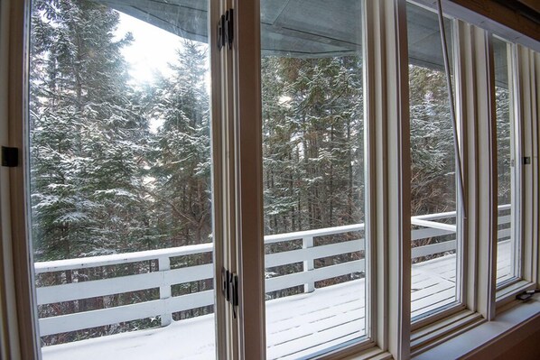 A room with large windows overlooking a snowy deck with a white railing.