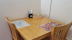 Una mesa de comedor de madera con dos individuales, uno con un mapa y el otro con un diseño de granos de café. Cuatro sillas de madera rodean la mesa.