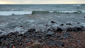 Una playa rocosa con olas rompiendo en la orilla.