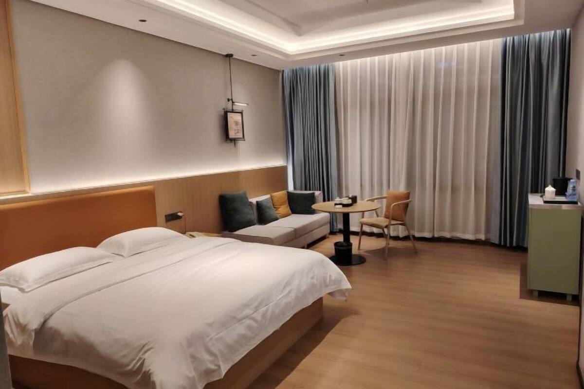 Una habitación de hotel con una cama grande, un sofá, una mesita y una silla.