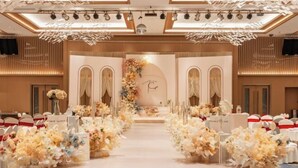 A wedding ceremony setup with floral arrangements, a central aisle, and a backdrop with a monogram. - Guangrong Hotel (Sanming)