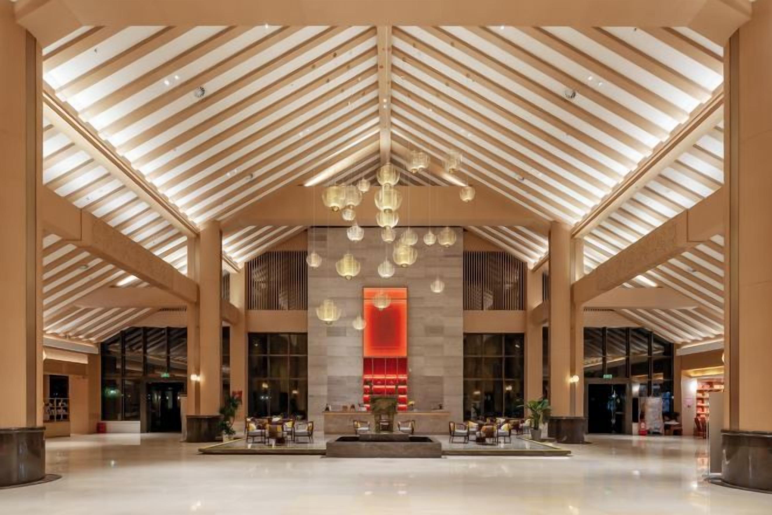 A spacious lobby with a high ceiling, large windows, and a central seating area.