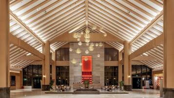 A spacious lobby with a high ceiling, large windows, and a central seating area.