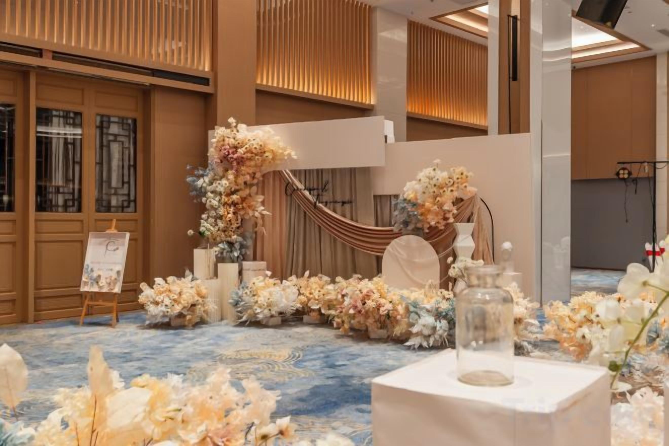 A room with a blue carpet, floral arrangements, and a white table with a vase.