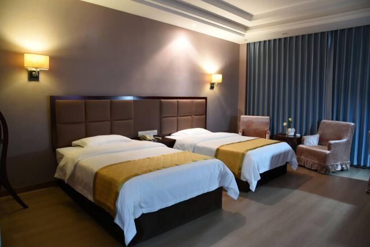 Una habitación de hotel con dos camas, un ventanal con cortinas y una silla.
