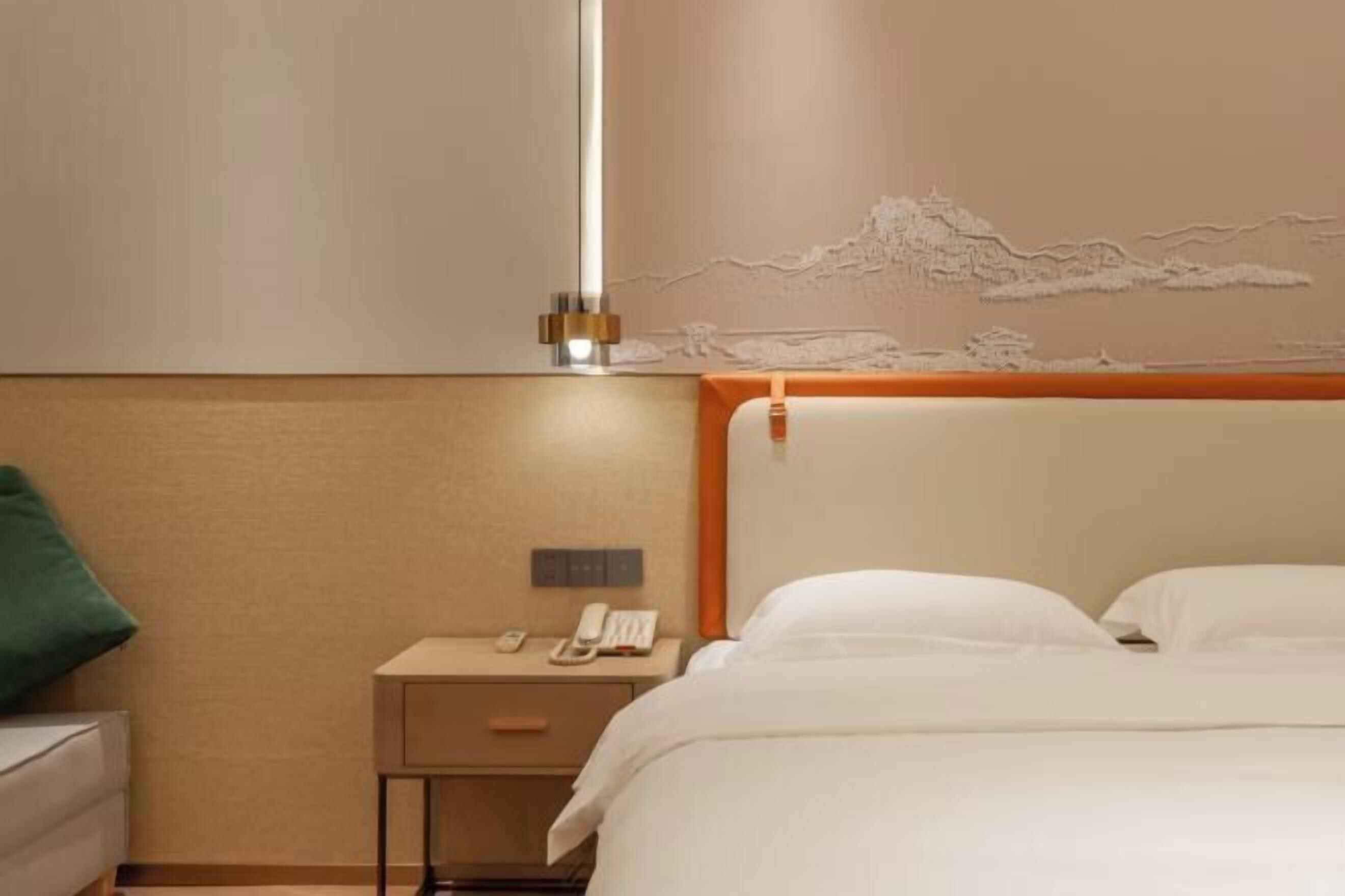 Habitación de hotel con cama, mesita de noche y teléfono en la pared.