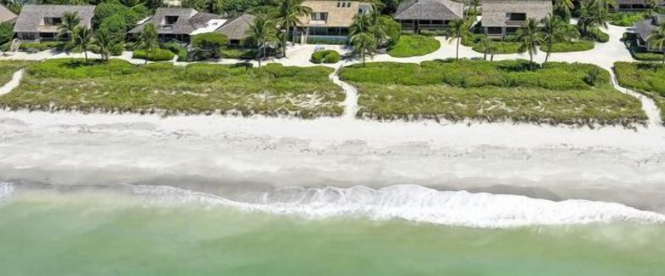 A coastal resort with beachfront villas, a sandy beach, and a clear view of the ocean.