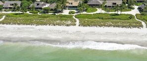 A coastal resort with beachfront villas, a sandy beach, and a clear view of the ocean.