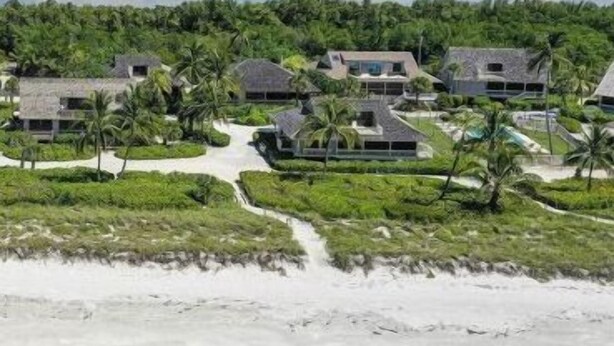 A coastal resort with multiple bungalow-style buildings surrounded by lush greenery and a beach. - South Seas Beach House 22 (Captiva)