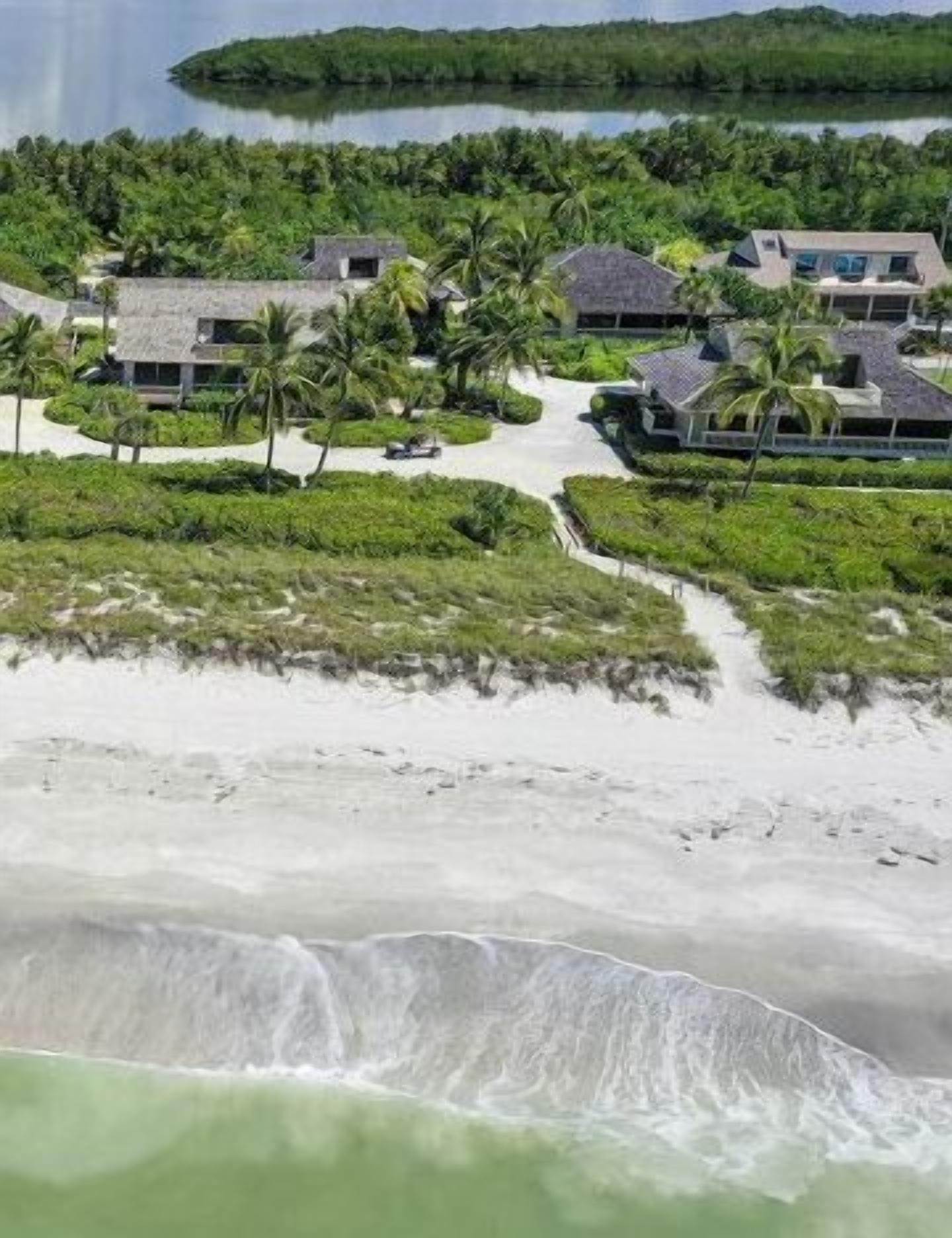 A coastal resort with multiple bungalow-style buildings, a sandy beach, and a view of the ocean.