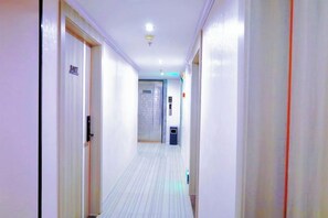 A corridor with doors on both sides, a trash bin, and a light fixture on the ceiling. - Danxia Holiday Hotel (Hezhou)