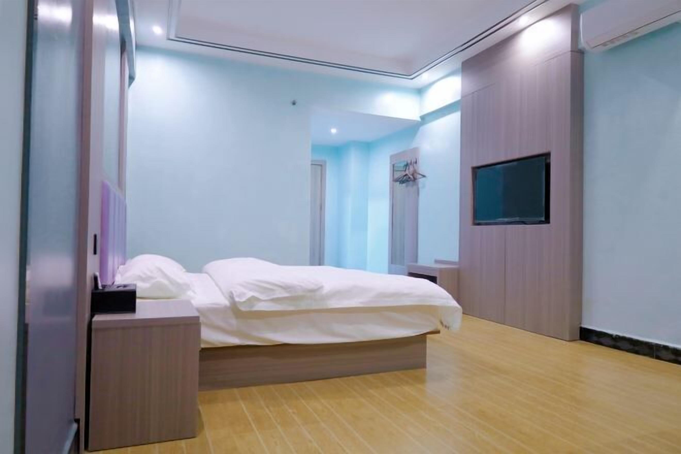Un dormitorio moderno con cama, mesitas de noche, televisor y armario.