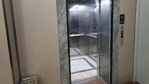 An elevator with a marble wall, a metal door, and a control panel with a red button. - Danxia Holiday Hotel (Hezhou)