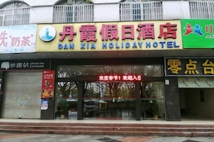 Un hotel con un letrero llamativo que dice 'Dan Xia Holiday Hotel' y una entrada visible.