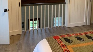 A room with a lofted sleeping area, a large window, and a mounted TV. - A beautiful Sunset Cottage. Amazing Mountain View’s and Sunsets. (Hendersonville)