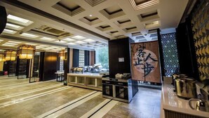 A modern hotel lobby with a central reception desk, a decorative wall with calligraphy, and a patterned floor. - Jilong Hotel (Longli County Traditional Chinese Medicine Hospital) (Longli)