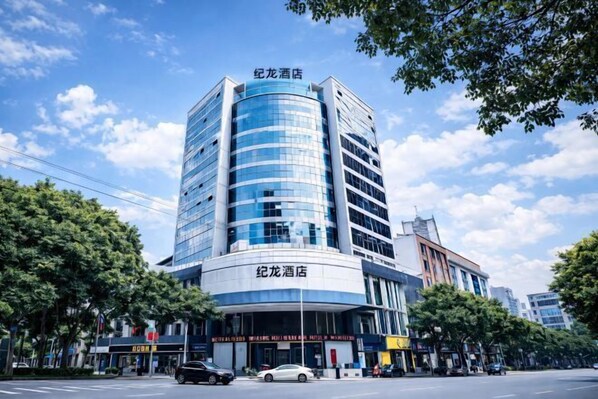 A modern hotel with a curved facade, multiple floors, and a prominent signage at the top. - Jilong Hotel (Longli County Traditional Chinese Medicine Hospital) (Longli)