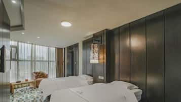 Habitación de hotel con dos camas, un ventanal grande con cortinas, piso estampado y un adorno en la pared.