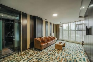 Una habitación de hotel moderna con un sofá de cuero, una mesita de madera y un suelo estampado.