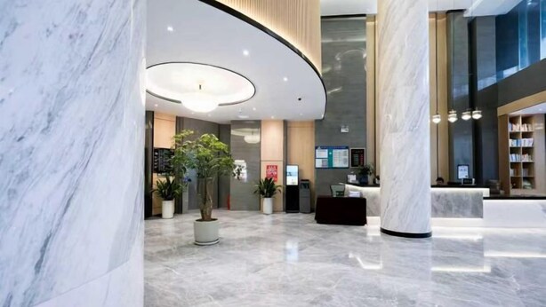 A modern lobby with marble flooring, a reception desk, and a large potted plant. - Jilong Hotel (Longli County Traditional Chinese Medicine Hospital) (Longli)