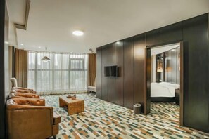 A modern hotel room with a large window, a flat-screen TV, a bed, and a seating area with chairs and a small table. - Jilong Hotel (Longli County Traditional Chinese Medicine Hospital) (Longli)
