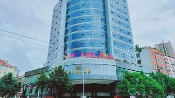 Un hotel moderno con fachada curva, varios pisos y una entrada destacada con señalización.