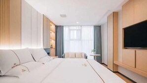 A hotel room with a large bed, a TV, a small table, and a view of the outdoors. - Jilong Hotel (Longli County Traditional Chinese Medicine Hospital) (Longli)