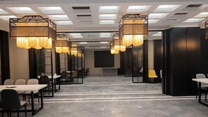 A modern conference room with rows of tables and chairs, decorative hanging lamps, and a large screen at the front. - Jilong Hotel (Longli County Traditional Chinese Medicine Hospital) (Longli)