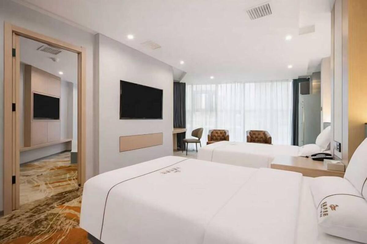 A hotel room with two beds, a TV, a desk, and a chair.