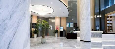 A modern lobby with marble flooring, a reception desk, and a large column.