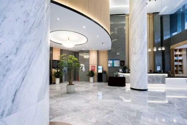 A modern lobby with marble flooring, a reception desk, and a large column. - Jilong Hotel (Longli County Traditional Chinese Medicine Hospital) (Longli)